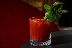 A Bloody Mary on a cocktail table with maroon carpet in the background. 