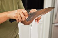 Slicing a piece of paper with a Mac Knife 8-Inch Hollow Edge Chef's Knife