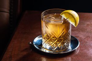 Scotch and water in a glass with ice and a lemon garnish