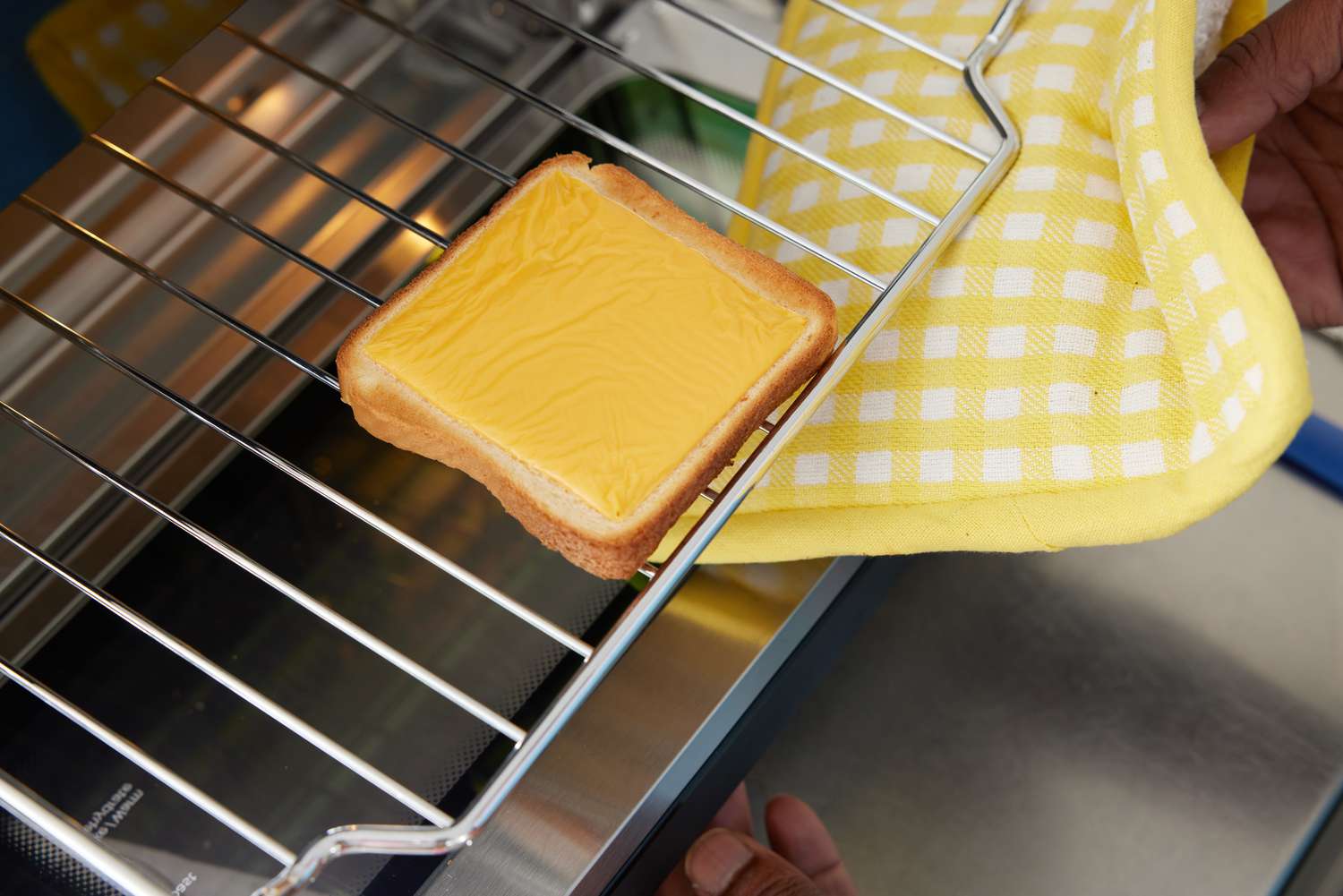 A hand pulling cheese toast from the Instant Pot Omni Plus 18L Air Fryer Toaster Oven