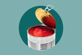 An open can of tomatoes on a green background. 