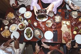 A group of people at dinner, with their phones out. 