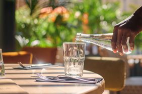 A person pouring water at a restaurant. 