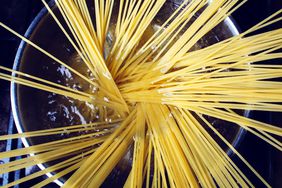 Spaghetti pasta being cooked in pot of boiling water.