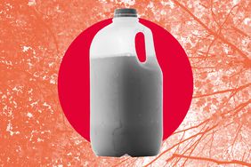 A jug of apple cider over a red and orange background showing fall foliage. 