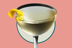 A white wine martini on a peach and pale green background. 