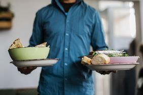 A server carrying bowls of food to some patrons.